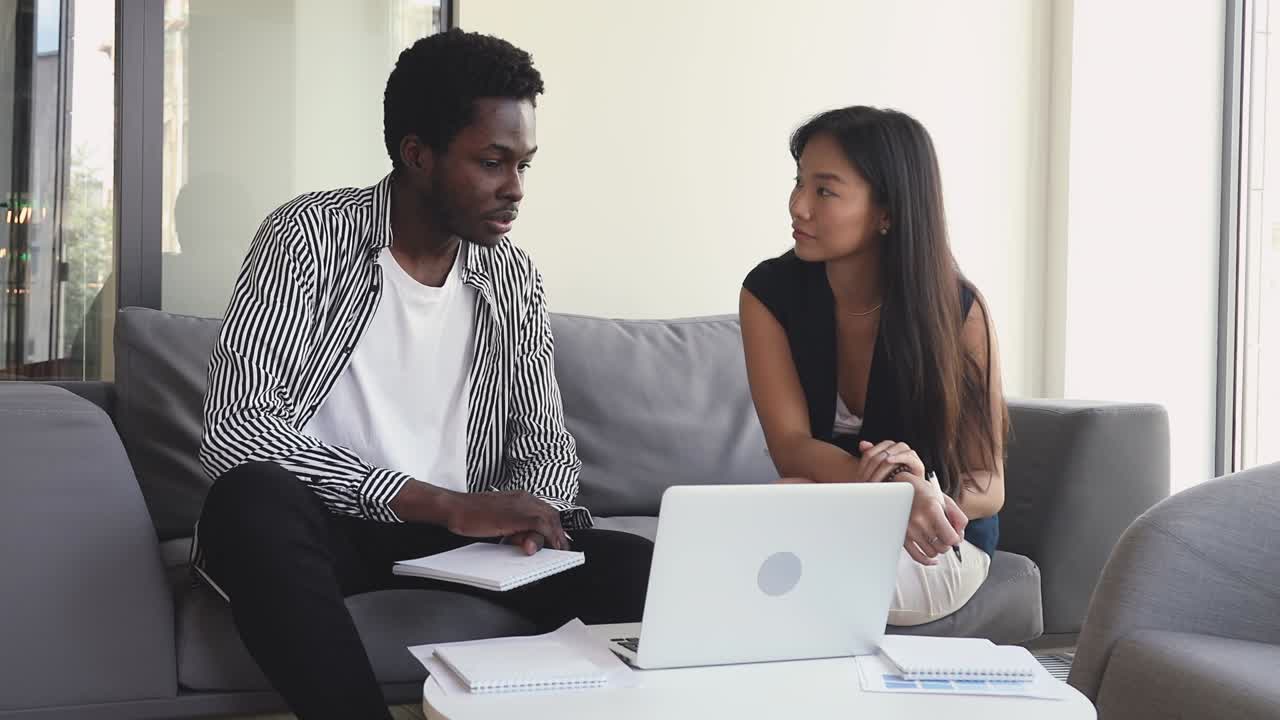 Happy young multiracial business partners discussing project details.