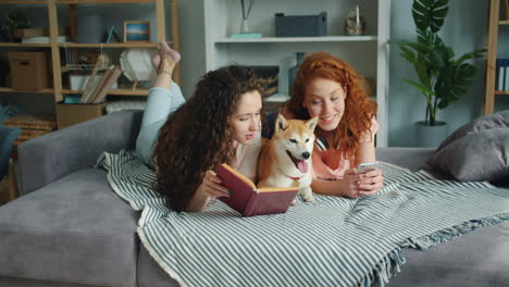 two young women relaxing with dog on couch