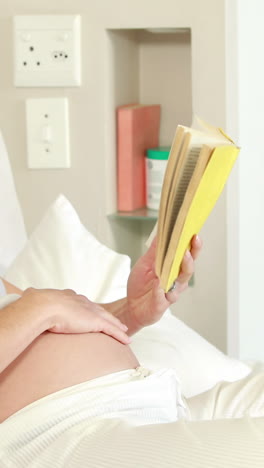 pregnant woman relaxing on bed reading