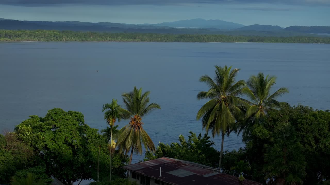 Coastal town Wewak Papua New Guinea PNG aerial drone Wewak Hill Boram road neighborhood village home buildings Harbor view Dogreto Bay Cape Wom morning blue canoe Bilum power boat upwards motion