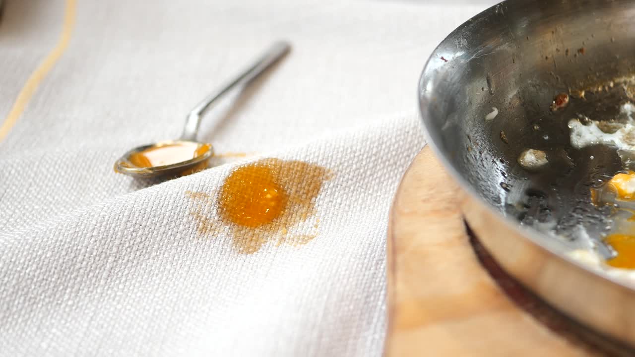 Spilled Scrambled Eggs and Oil on a Tablecloth
