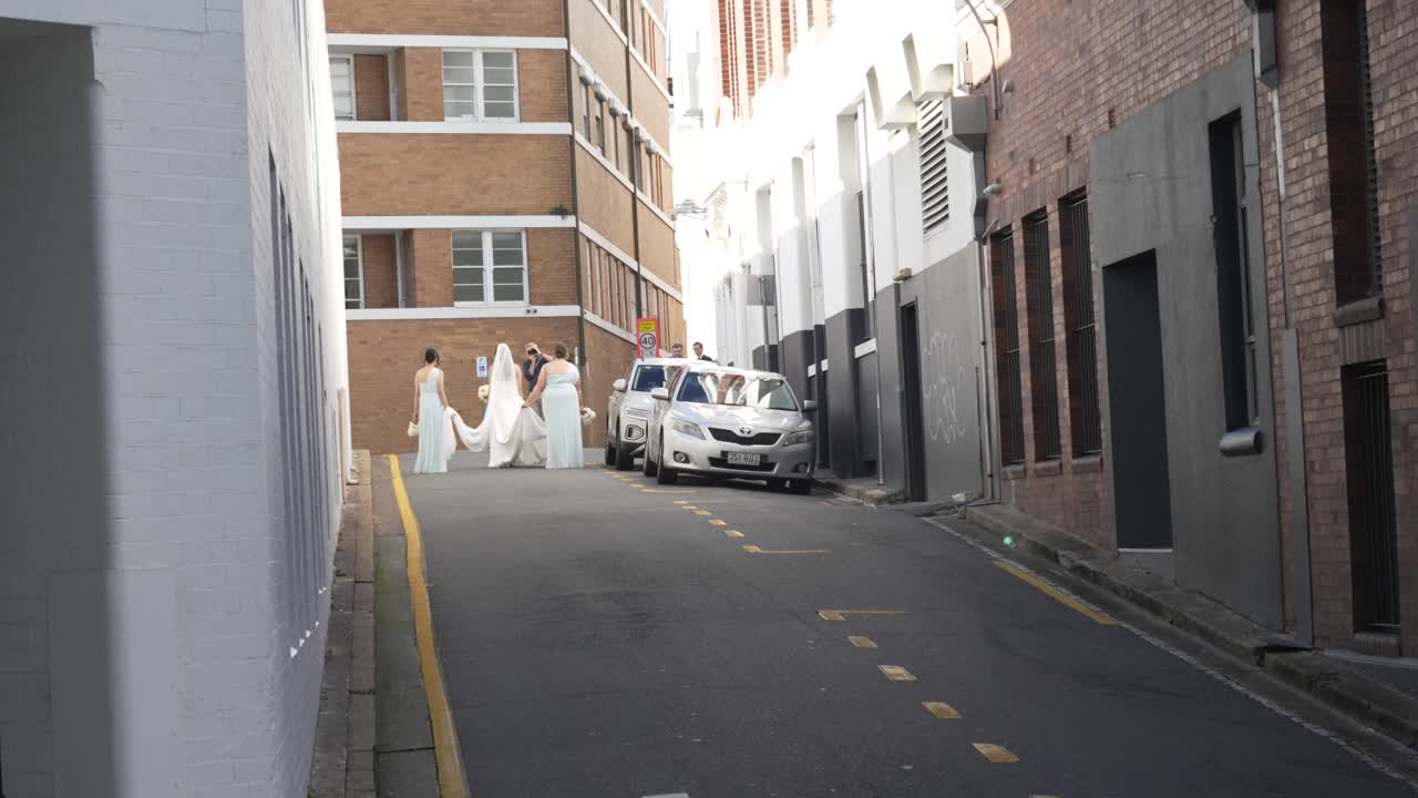 Bride and Bridesmaids Walking Down a City Alley on Their Wedding Day