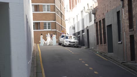 bride and bridesmaids walking down a city alley on their wedding day