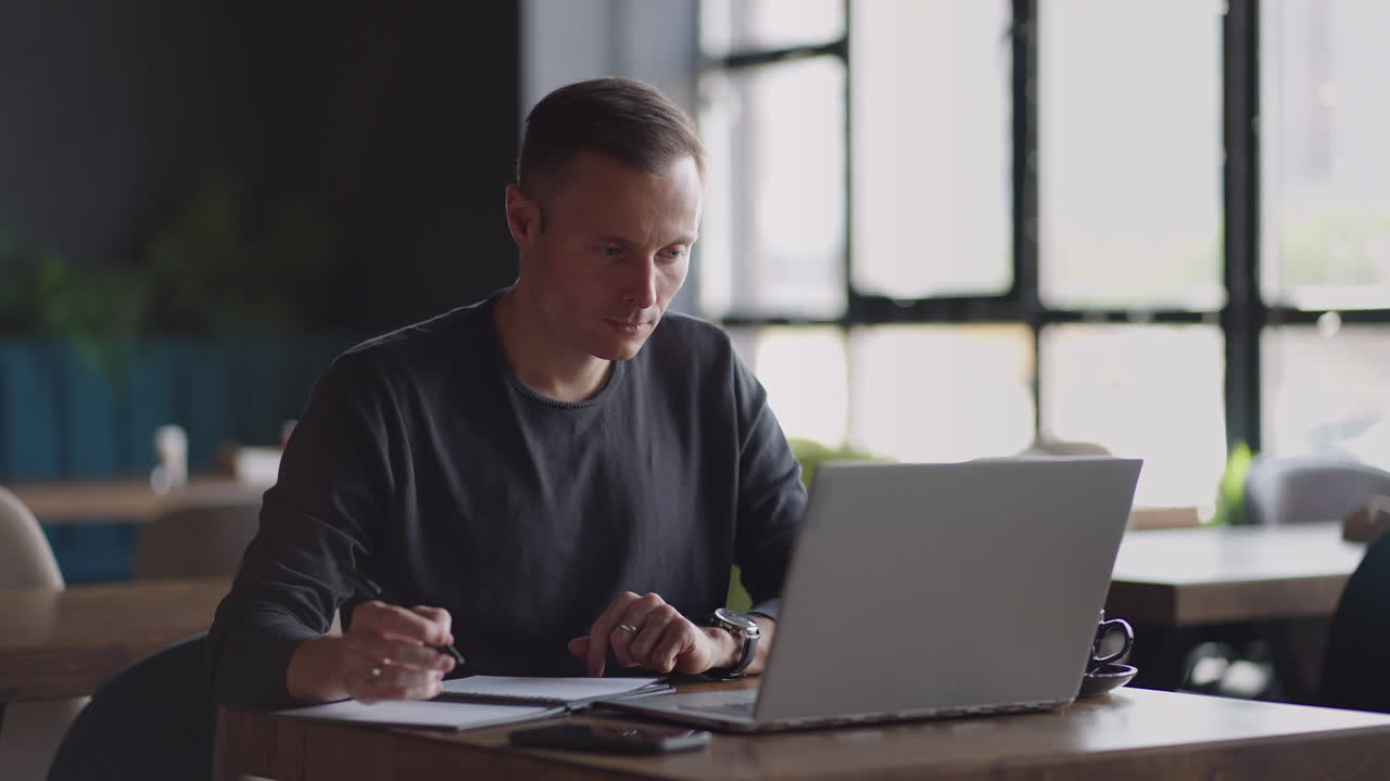 Smiling man with works from home in his kitchen using a laptop. Remote work and remote learning. remote work during self-isolation in quarantine man works with financial documents.