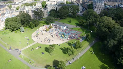 Toma-Aérea-Del-Parque-Infantil-En-Los-Prados-De-Edimburgo,-Lleno-De-Niños-Jugando,-En-Un-Día-Soleado-De-Verano-|-Edimburgo,-Escocia-|-4k-A-30fps