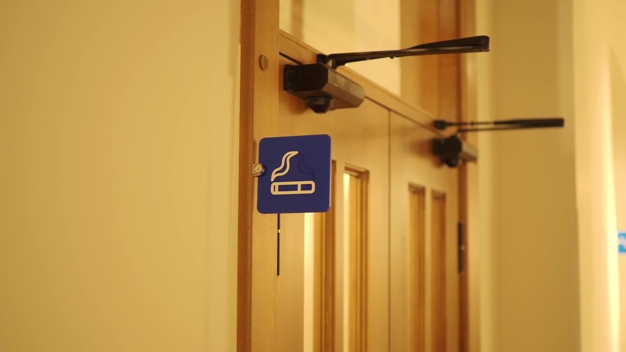 Cartello blu "Area Fumatori" su una porta di legno
