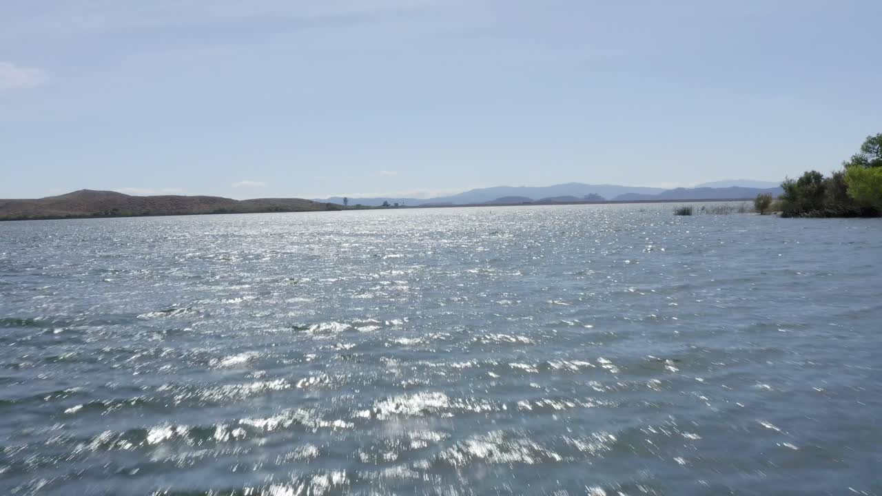 아름다운 공중 드론 샷, 호수 위를 낮게 날고 있는 드론이 레이크 스키너 - 테메큘라 - 리버사이드 카운티 - 캘리포니아에 있는 산을 향해 날아갑니다.