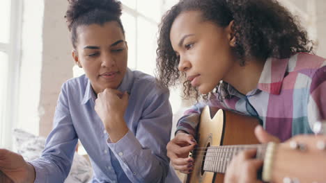 teenage girl learning guitar from a woman