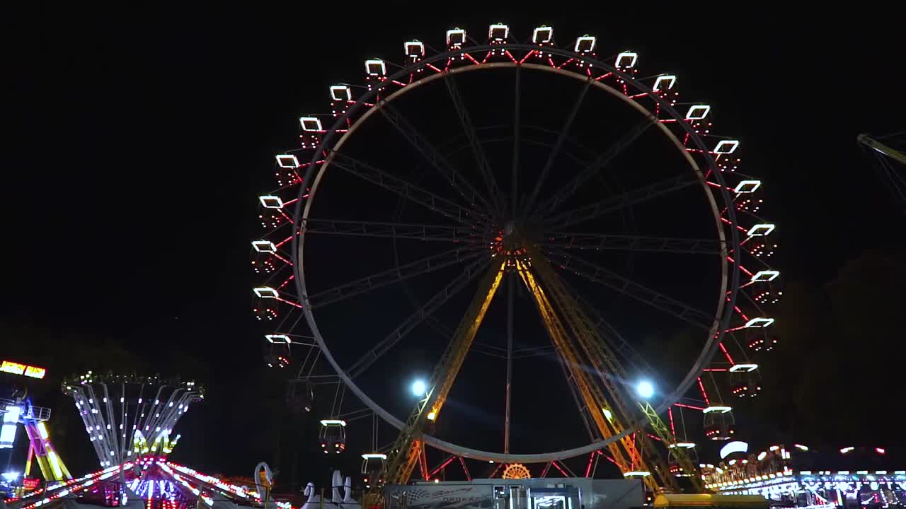 Rotating ferris wheel at amusement park with neon lights