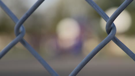 Rack-focus-into-an-empty-school-playground-on-a-sunny-day-from-a-chainlink-fence