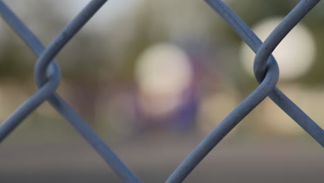 rack focus into an empty school playground on a sunny day from a chainlink fence