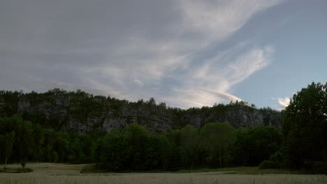 Calm-time-lapse-of-cornfield,-trees-and-mountains-at-sunset-time