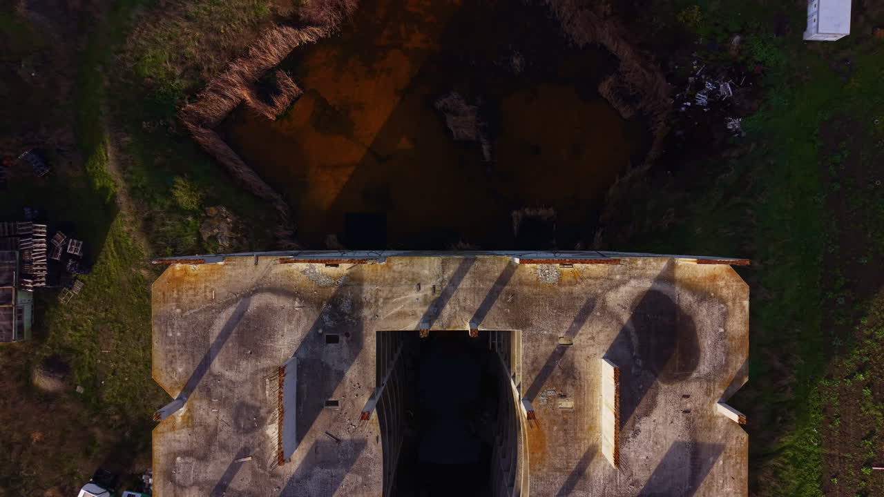 Abandoned industrial site with a haunting waterway reflecting shadows of decay and nature's reclaim in golden hour light