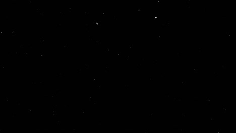 pequeños copos de nieve, nieve real aislada para su inserción en un proyecto de invierno, copos de neve en un fondo negro en 4k