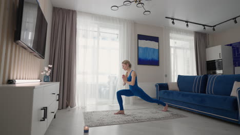 entrenamiento de yoga en casa en la alfombra por la tarde cerca del sofá y la televisión en la sala de estar. ejercicios matutinos y clase de yoga. ejercicios complejos de yoga para el equilibrio y la resistencia