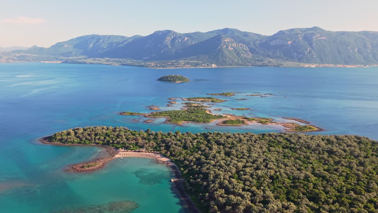 Drone captures a vibrant beach bar near Lichadonisia island with the majestic mountains of Sterea Ellada rising beautifully in the distance