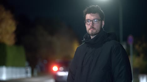 young man stands alone in chilly munich suburb during frosty winter night, street and car lights create vivid illumination