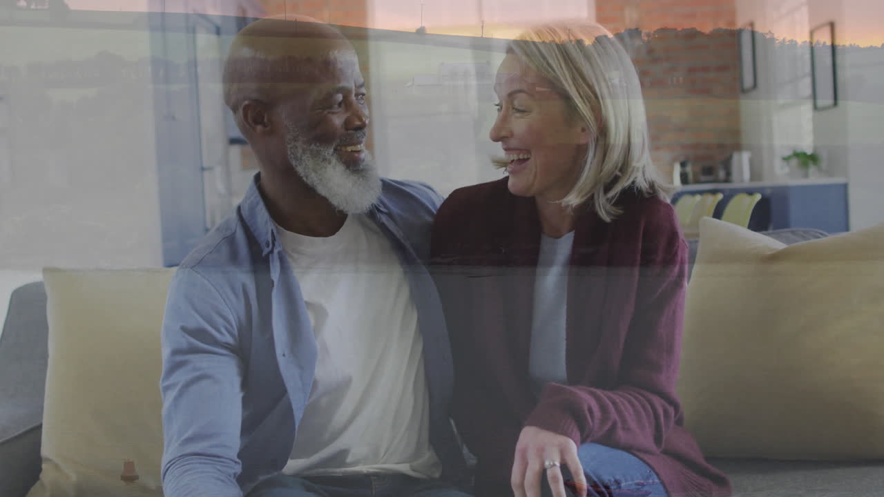 Couple sitting on couch watching animation, sharing joyful moment at home