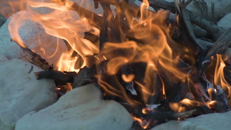 campfire made from wood and a surrounded by small rocks, shot with slow motion in a selective focus