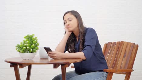 Indian-girl-scrolling-phone-at-a-cafe