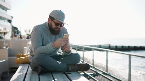 man using smartphone on a beach cafe