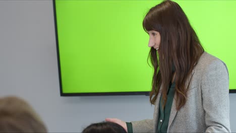 mujer de negocios presentando a sus colegas con pantalla verde