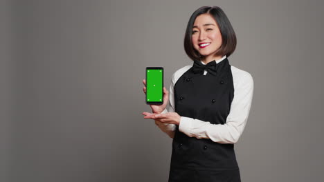 Restaurant-hostess-presenting-smartphone-with-greenscreen