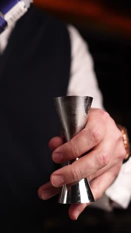 bartender measuring liquor with jigger