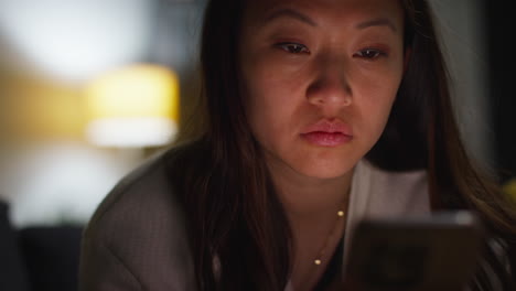 close up of woman spending evening at home sitting on sofa with mobile phone scrolling through internet or social media 5