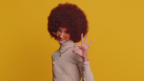 young funny school girl in glasses looking approvingly at camera showing okey gesture, like sign