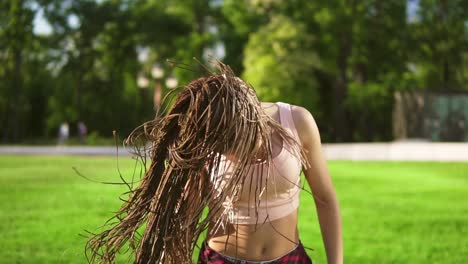 young beautiful girl with dreads dancing in a park. beautiful woman listening to music and dancing during a sunny day