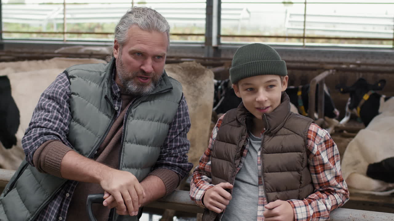 Father and Son Farmers in a Cow Barn