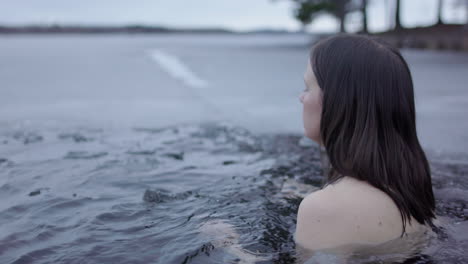 a woman enters the icy lakewater and steadies her breathing