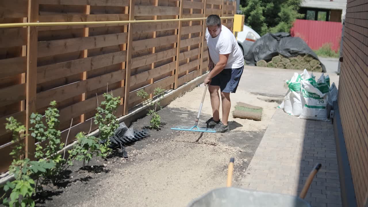 jardinero colocando césped en el patio privado con valla de madera