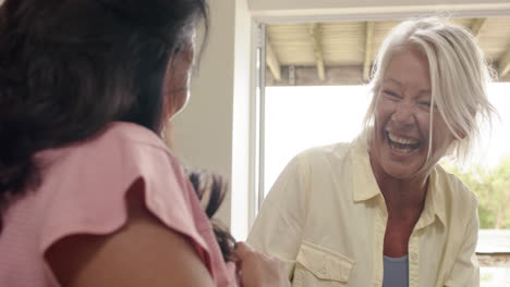 Happy-diverse-senior-women-laughing-on-sofa-in-sunny-living-room,-slow-motion