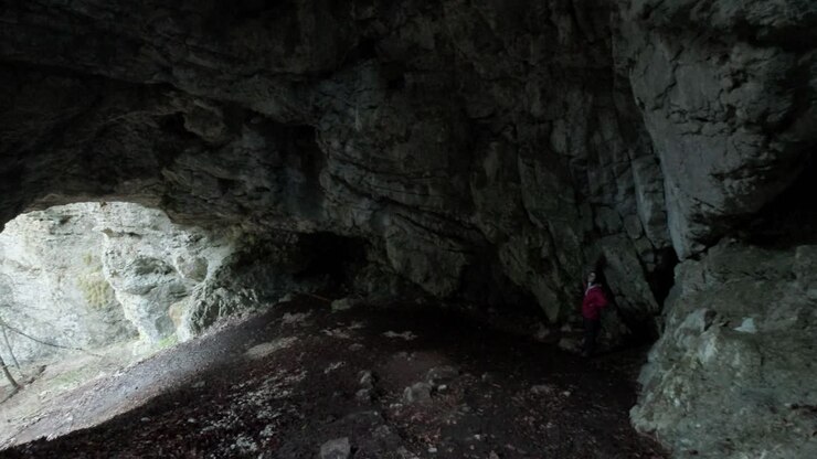 Lady standing in Pokljuka Cave with the camera panning from right to left to show the cave entrance. Pokljuka Gorge in Slovenia Triglav National Park