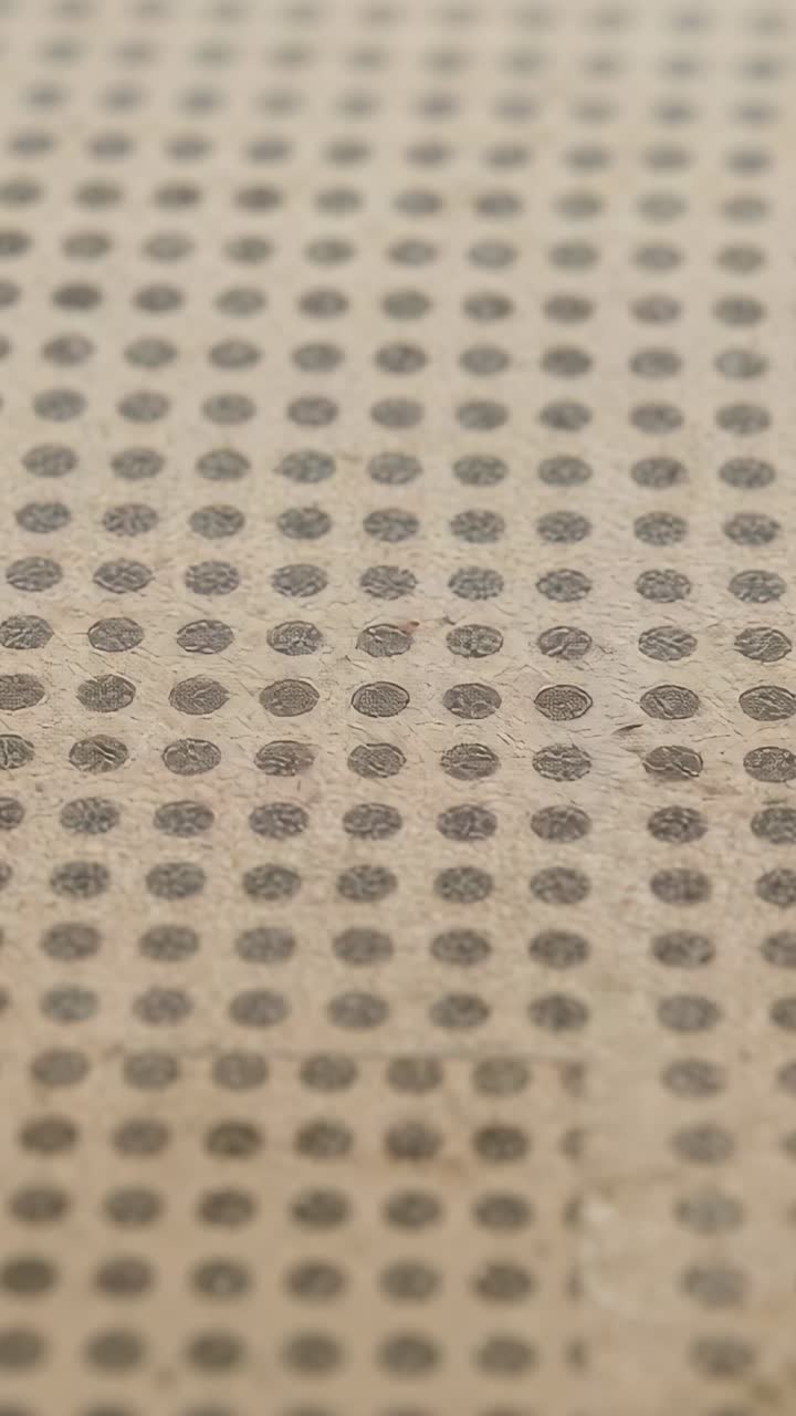 Vertical video: Recording camera filming tan cloth in closeup adjusting focus showing dots and seam