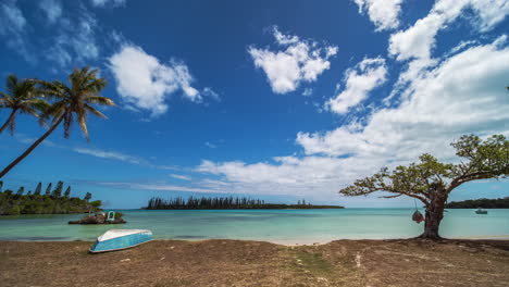 A-stunning-lagoon-in-a-tropical-paradisiacal-island-with-palm-trees,-a-lone-evergreen-and-columnar-pines-on-a-distant-isle---time-lapse