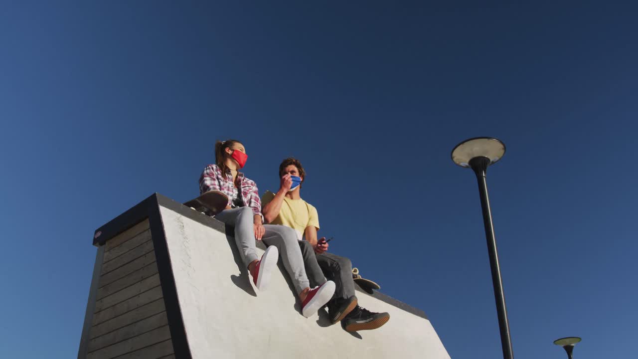 feliz mujer caucásica y amigo hombre con máscara facial, sentado y riendo