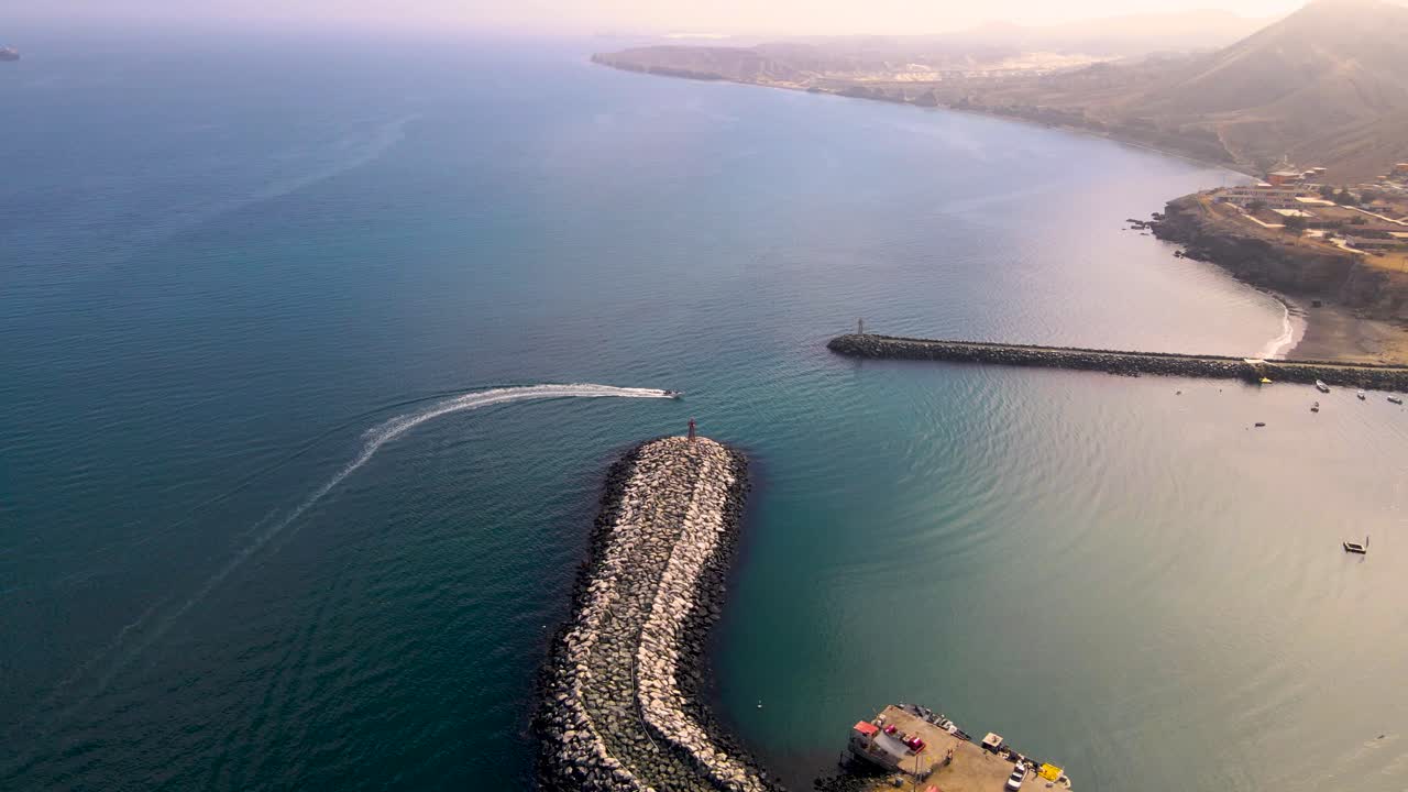 Aerial high angle overview of Cedros Island dock surrounded by turquoise waters, showcasing fishing activity below as boat enters harbor