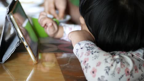 child using a tablet at a family meal