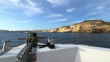 point of view of sailboat bow navigating toward corsica island cliffs and capo pertusato lighthouse in france, 50fps-1