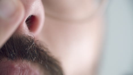 un primer plano extremo de un hombre que se corta el pelo de la nariz con unas tijeras afiladas