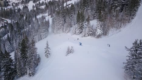 skiers and snowboarders race down the side of a snow packed mountain side in utah