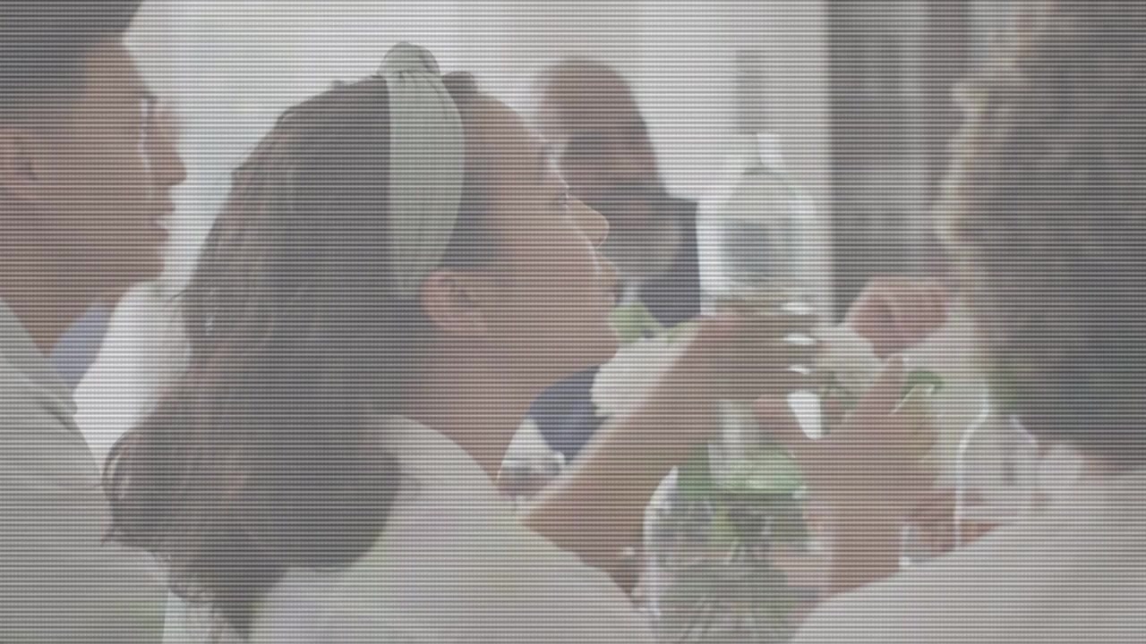 ダイニングテーブルに座って談笑する友人たち。ヘッドバンドの女性がボトルに手を伸ばして分け与え、グラスがカチャカチャと音を立てる。