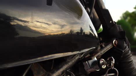 close up slider shot of motorcycle tank reflecting sunset