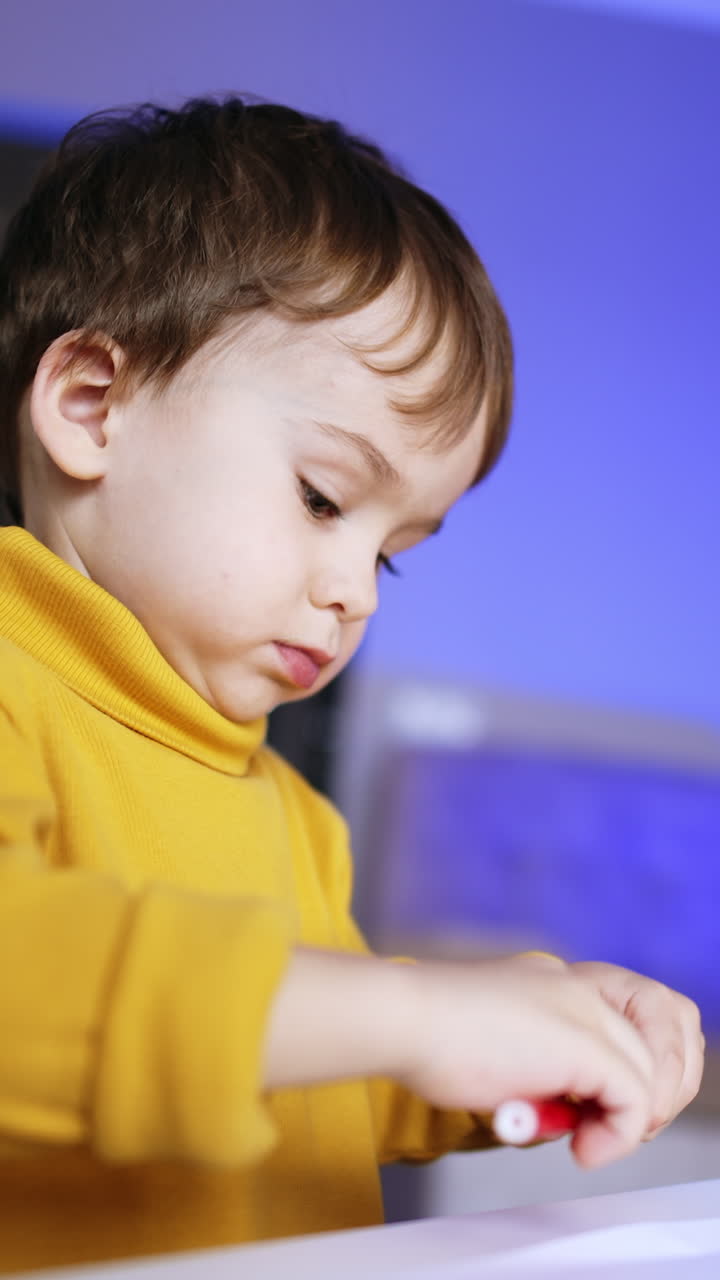 Bambino concentrato con maglione giallo che usa un pennarello