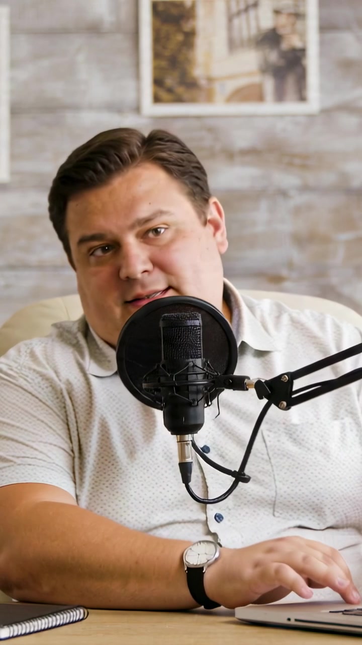 Video verticale: La registrazione inizia, il presentatore parla nel microfono con filtro anti-pop al tavolo, facendo podcasting con un laptop.