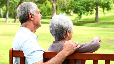 retired couple sitting on a park bench together