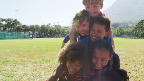 amigos de la escuela pre-adolescentes acostados en una pila en un parque